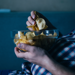 Close-up image of person holding bowl of potato chips