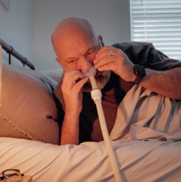 Man putting a CPAP nasal mask on his face while lying in bed