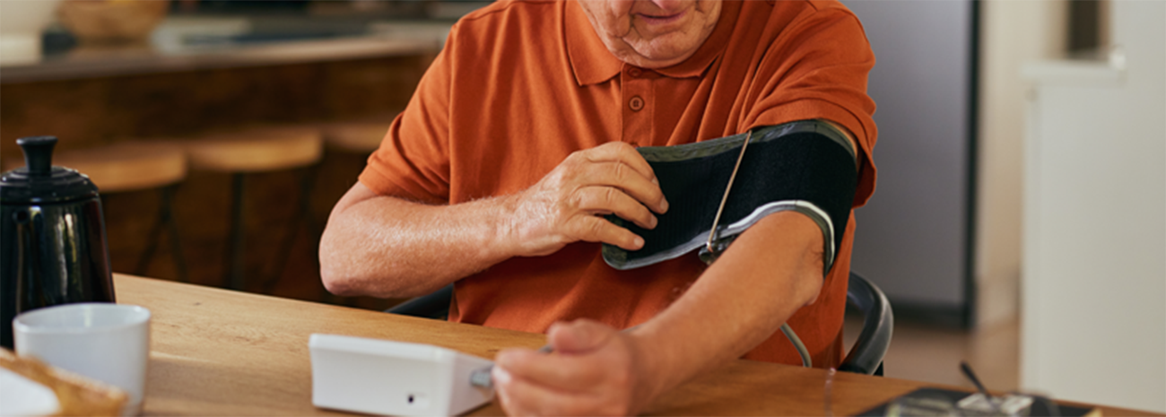 Image of an older man tightening a blood pressure cuff on his upper arm