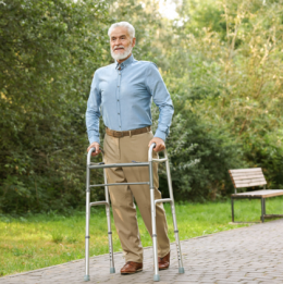 Older man with a walker strolling through the park
