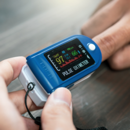 Person putting blue pulse oximeter on their finger