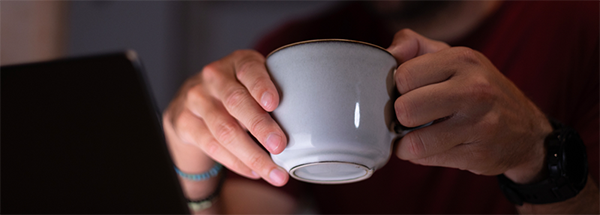 Man's hand with coffee cup held in it at night