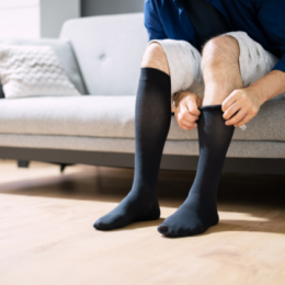 Man sitting on couch and pulling up black compression socks