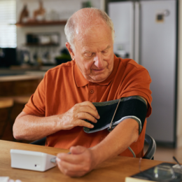 Image of an older man tightening a blood pressure cuff on his upper arm