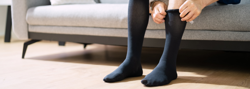 Man sitting on couch and pulling up black compression socks