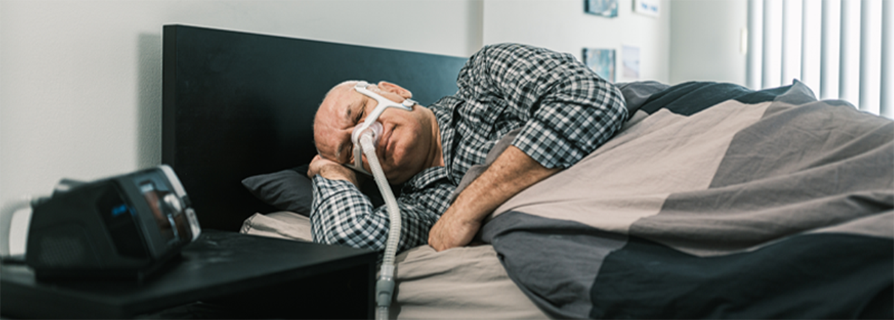 Man sleeping on his side in bed with a CPAP mask on
