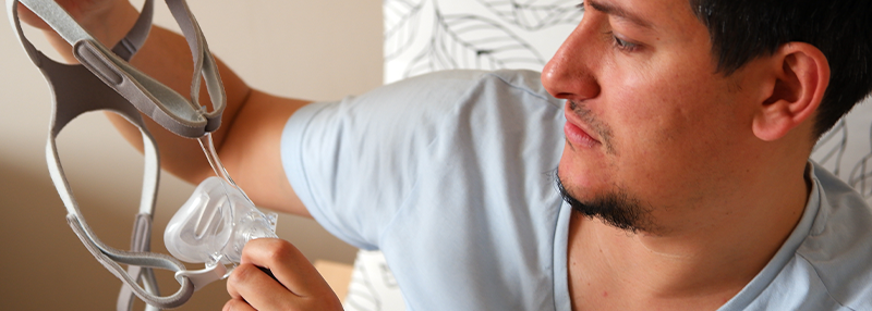 Man holding his CPAP mask and looking at it in confusion