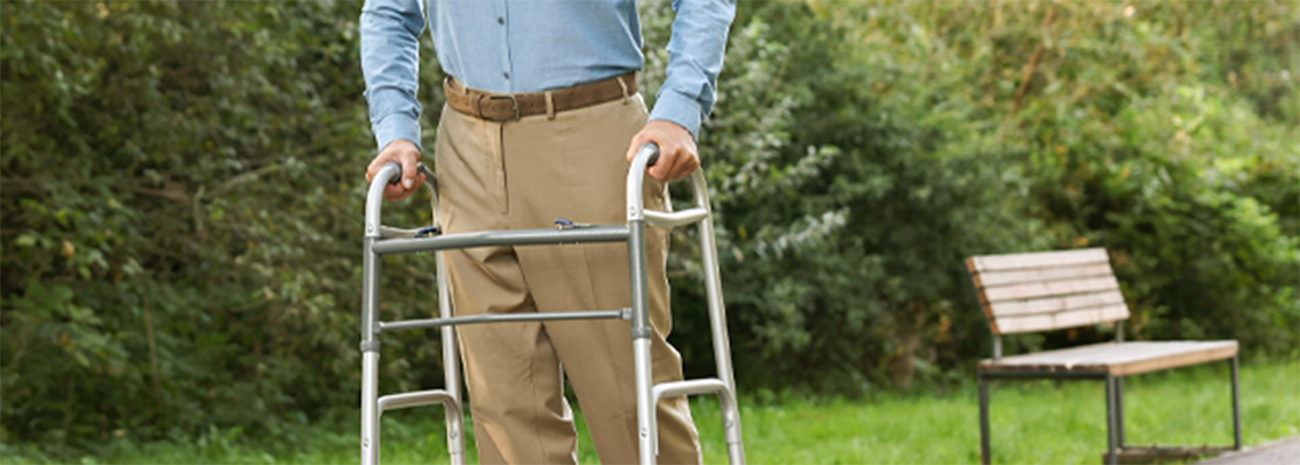 Elderly man with a walker strolling through the park