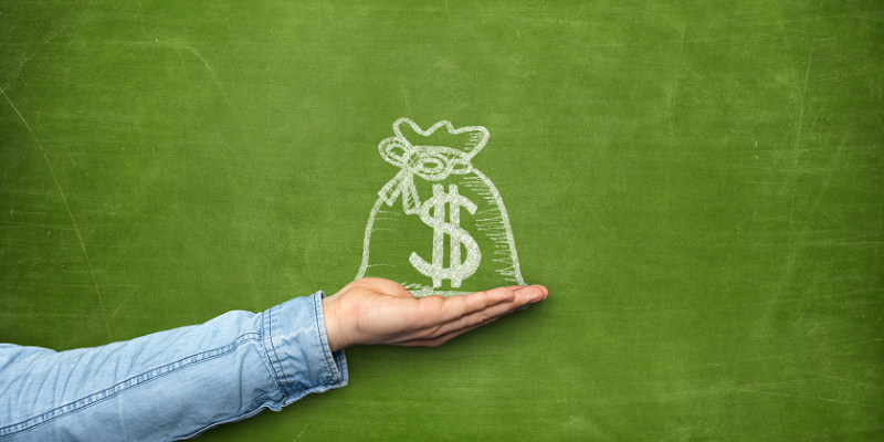 Photo of a person holding up a bag of money that is drawn on a chalkboard.