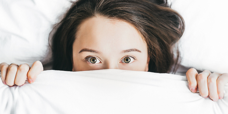 Photo of a girl with covers pulled up to her eyes.