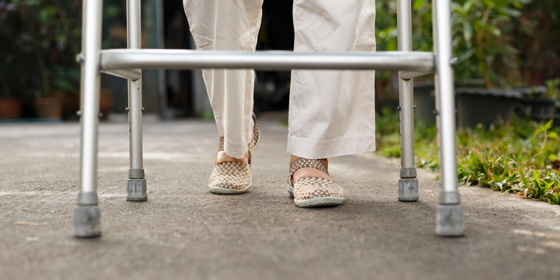 Photo of a person walking outside using a walker.