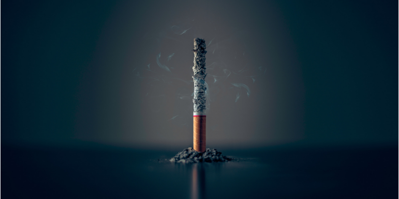 Photo of a burning cigarette against a black background.