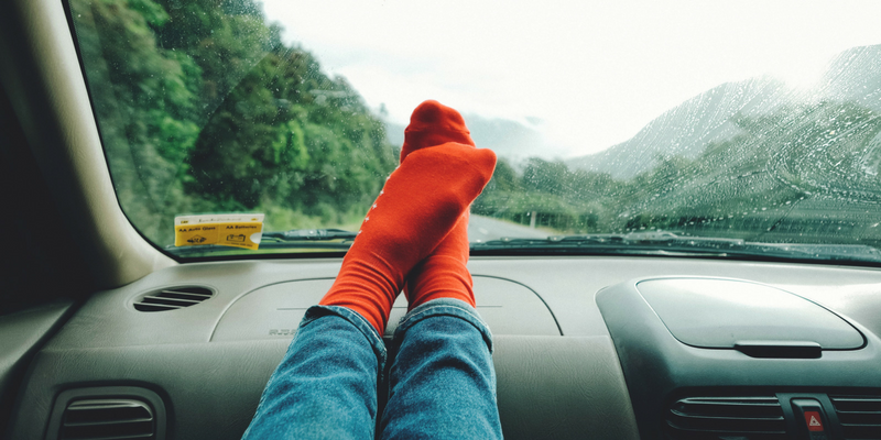 Person sitting in the car with their feet on the dash, wearing orange socks.