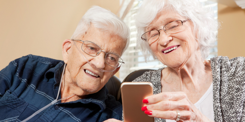 Photo of an elderly couple sitting together looking at a smartphone.