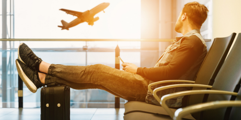 Photo of a man sitting in the airport on his phone.