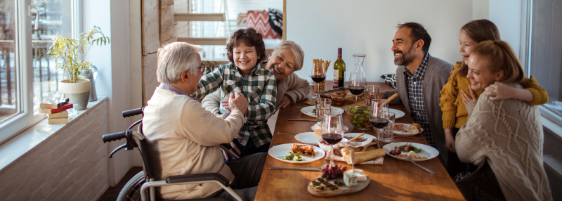 Senior in a wheelchair gathered at the table with their family over the holidays
