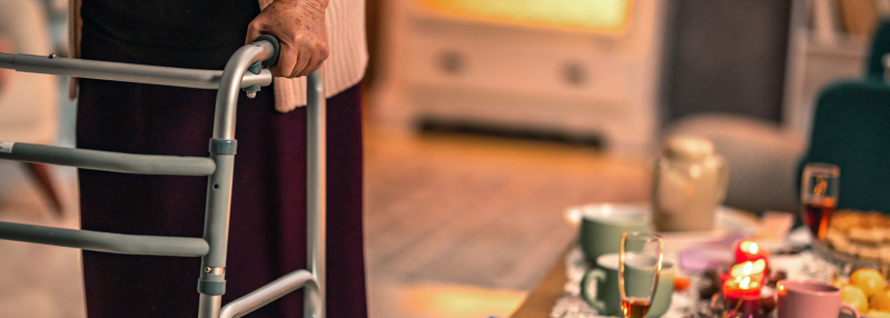 Elderly woman with her hands on a walker in her living room during Christmas
