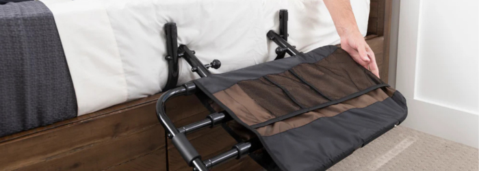 Bed rail with organizer on the side of bed and hand reaching for it