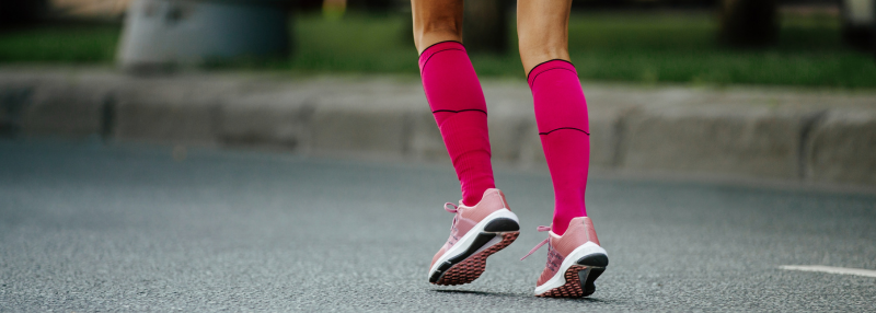 Woman wearing hot pink compression socks running outdoors