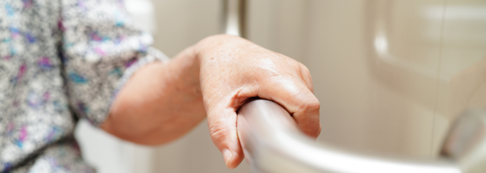 Senior woman using grab bar with close up of her hand on grab bar