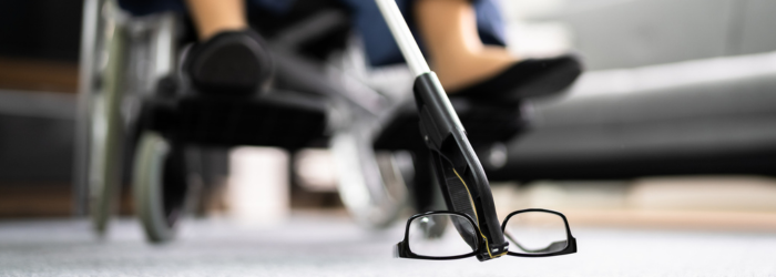 Woman in wheelchair using a reacher to pick reading glasses off the floor